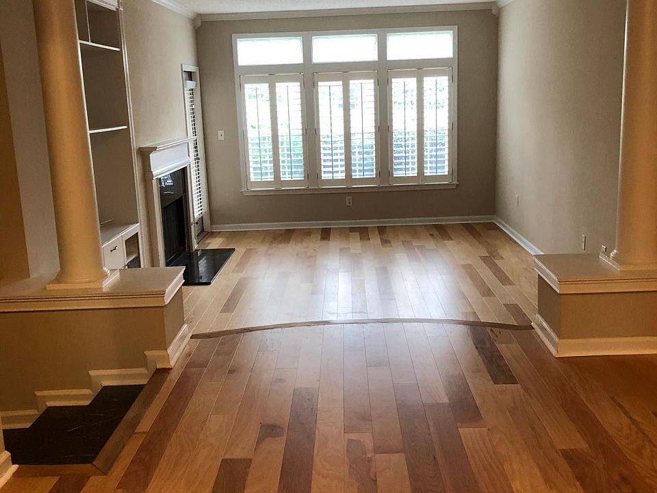 Large open living area with media cabinet, marble fireplace, and large windows