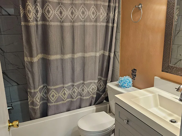 Full bathroom with tub/shower combo, tile surround, vanity with storage, and a window for natural light and ventilation.