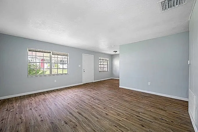 Bright and inviting living area with large windows and elegant wood flooring, perfect for relaxation and entertaining.