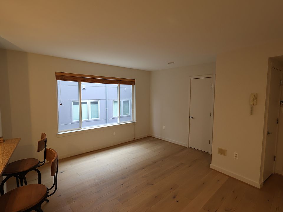 Living room. Front door located on the far right of the image, storage closet next to it. Door in the middle leads to bathroom #1, counter on left is open to kitchen.