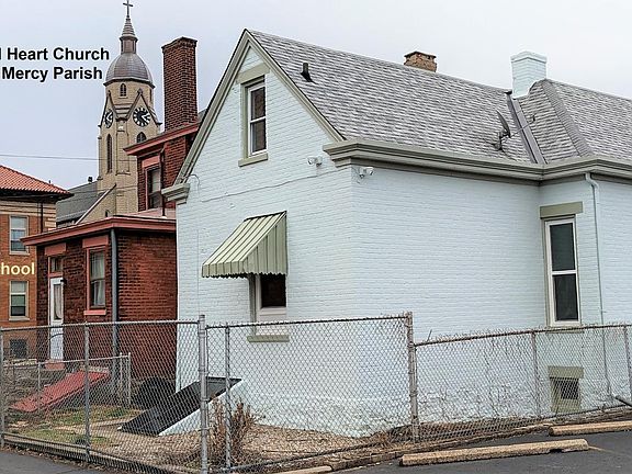The back of the house is surrounded by the parking lot for Holy Trinity Elementary School and Divine Mercy Parish.