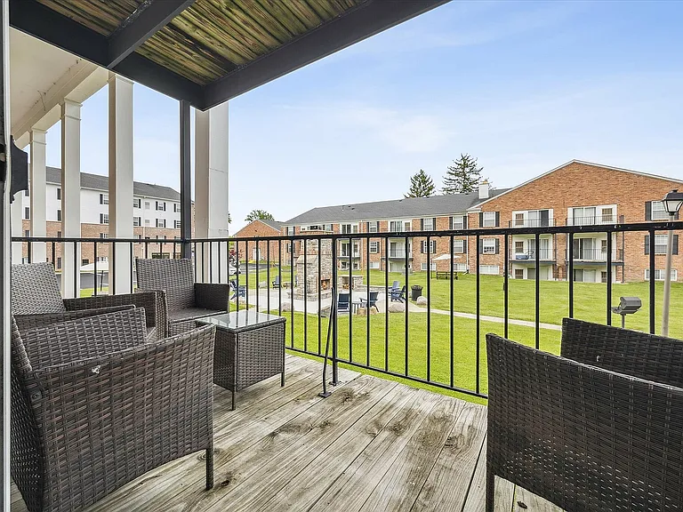 Charming apartment balcony overlooking a lush green courtyard, perfect for relaxing outdoors.
