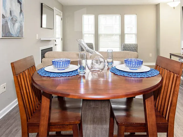 View of dining area of great room with large, bright window in the background and plank flooring