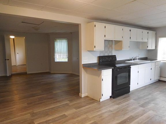 Kitchen with electric stove and refrigerator opening to the living room