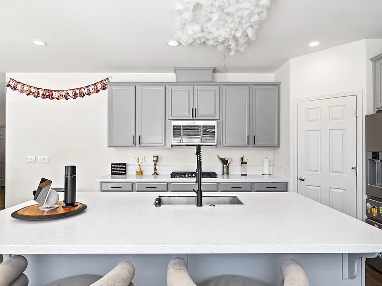 gourmet kitchen includes quartz counters, stainless steel appliances, double ovens, a large island, and modern cabinetry.