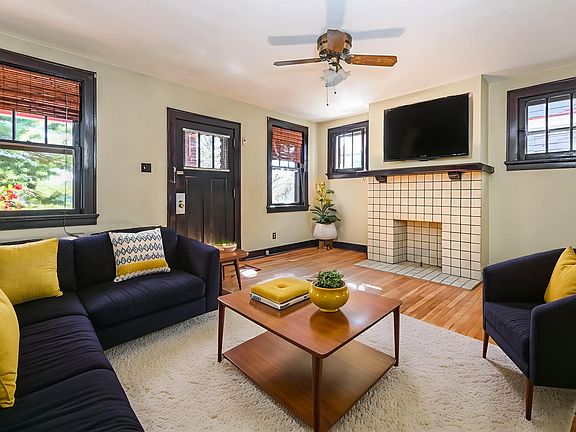 Large living room with a welcoming front door off the porch, opening into a formal dining area that can easily expand into additional living space. Original hardwood floors and classic character create an open, timeless feel throughout.