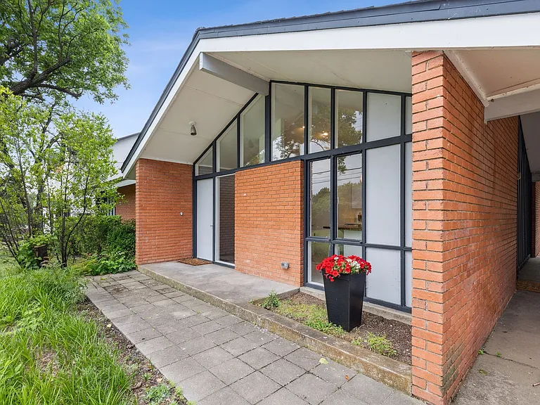 Mid-century modern architecture featuring a brick exterior and a prominent A-frame entry with expansive windows