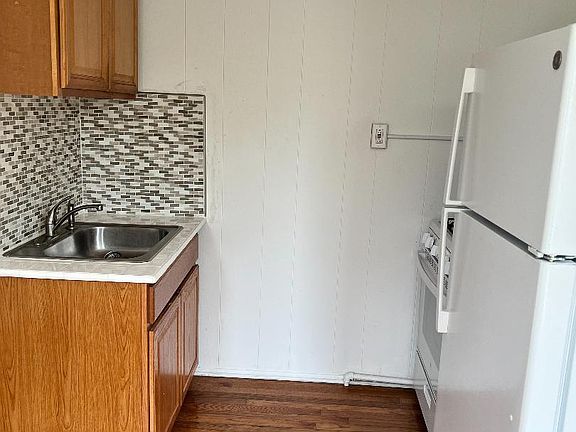 Kitchen with brand new refrigerator, stove and sink. Hardwood floors and ceiling fan.