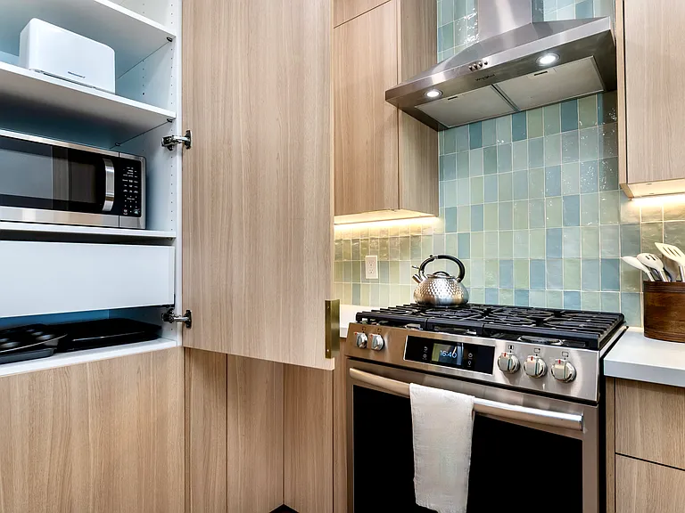 The pantry with a microwave, toaster, and drawers of cookware.