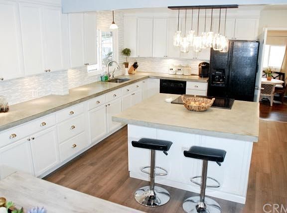 Remodeled kitchen includes all new cabinets, glass/stone back splash, concrete countertops, large island with storage, new light fixtures, new faucet and deep sink.