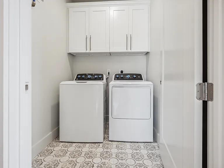 Large laundry room with side by side washer and dryer and custom cabinetry.