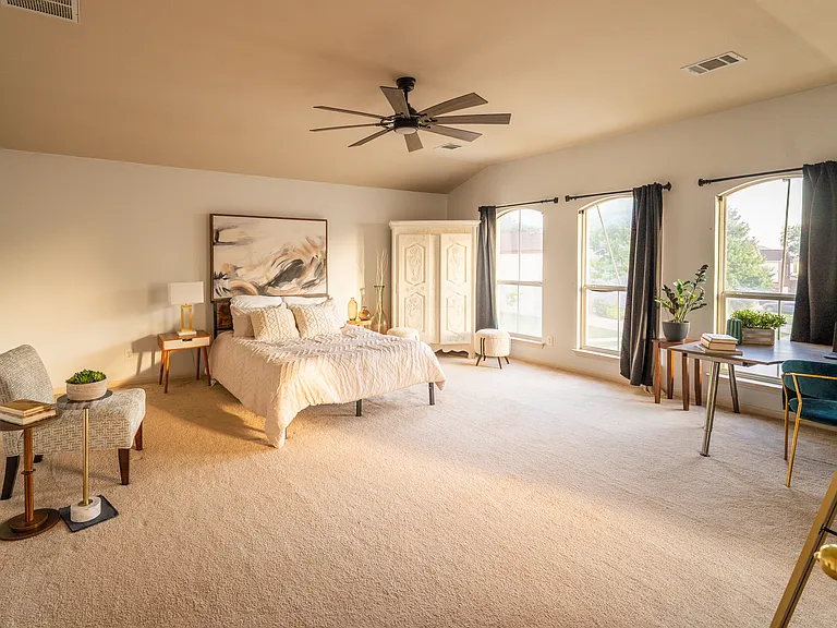 Grand Primary Suite: An exceptionally large primary bedroom retreat featuring vaulted ceilings, plush carpeting, and expansive windows. Includes a dedicated area perfect for a workspace or vanity, plus private double-door access to the en-suite bathroom.