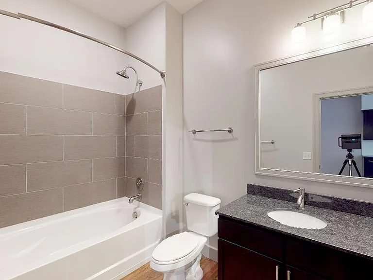 Apartment bathroom with large soaking tub and wood-style flooring.