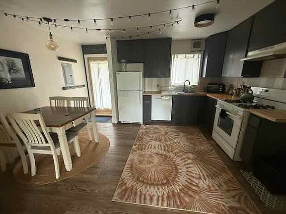 Newly refreshed eat-in kitchen with gas range and new tile backsplash. Well stocked with pots and pans and other cooking and baking basics. Exterior door opens to back side yard.