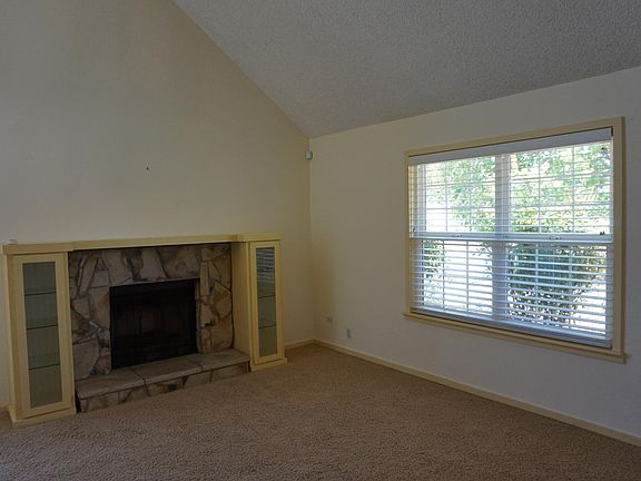 Living room has vaulted ceiling and fireplace.