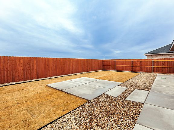 Backyard fire pit patio w/ lawn, rock drainage borders and covered porch.