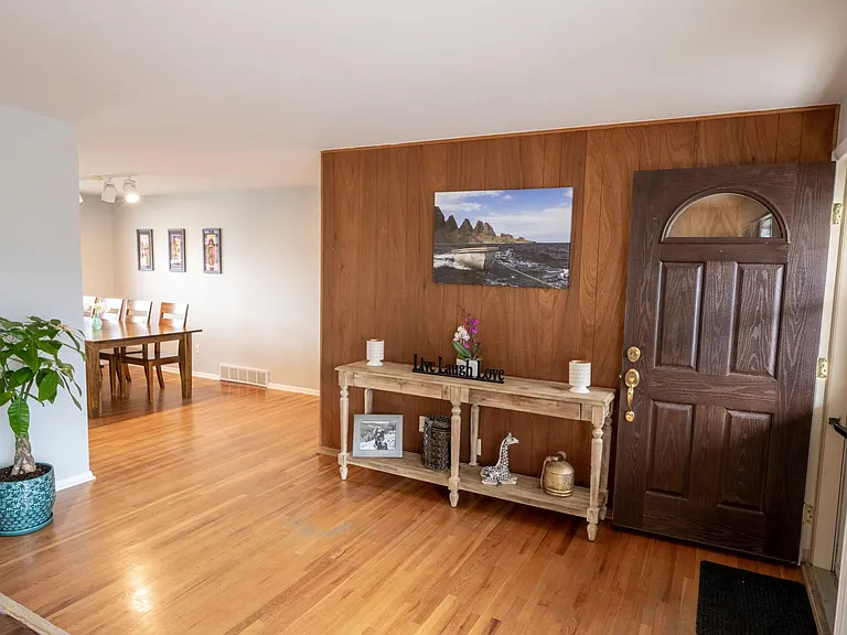 View from the living room towards the front door, dining room, and hallway towards the bedrooms.