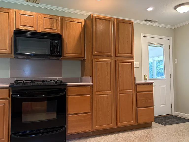 Well-designed kitchen with extensive cabinet storage, pantry cabinetry, gas range, built-in microwave, and convenient access to the laundry room and covered carport.