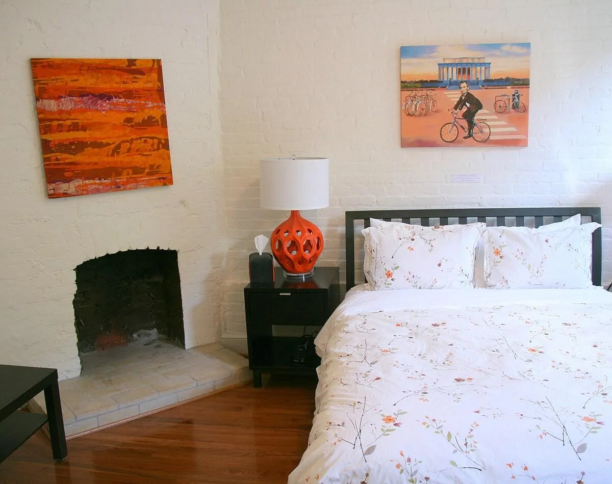 FRONT BEDROOM: hardwood floor, exposed brick wall, fireplace, and two south facing windows. - 2137 N St NW #1