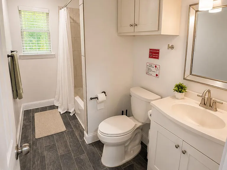 Well-appointed bathroom featuring a shower/tub combo, vanity with storage, and a window for natural light.