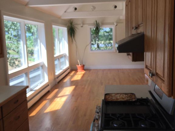 View from kitchen through dining area on into the living room area. New stove and redone wood floors.
