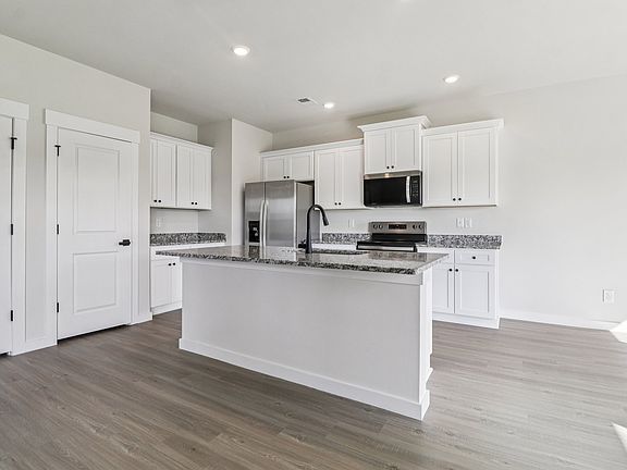The kitchen has stainless steel appliances and plank flooring.