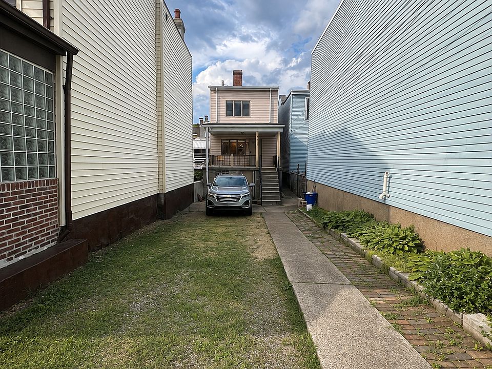 Front of house - tucked between two other houses - ability to park 4 cars in private driveway - small garden on right side
