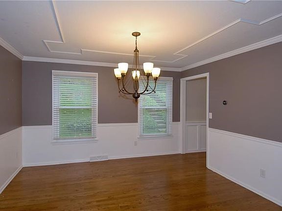 The dining room is enhanced with warm tones, a unique ceiling, wainscoting, crown molding and chair rail.