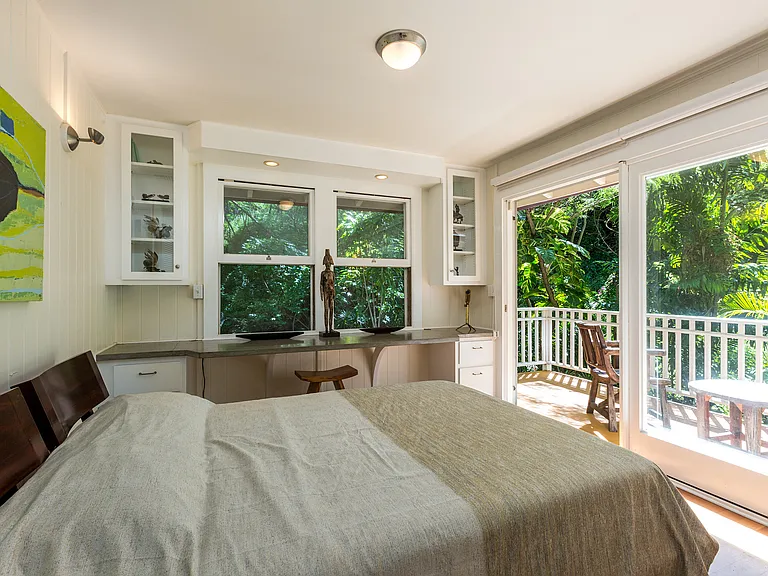 First bedroom with queen bed on the main floor has a large walkout balcony surrounded by lush greenery