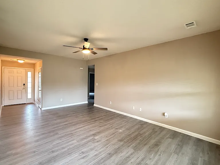 Spacious, open living room area featuring brand-new luxury vinyl plank (LVP) flooring and a modern ceiling fan.