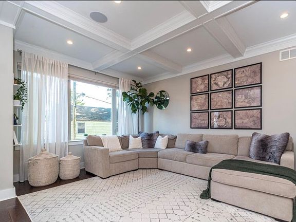 Spacious living room, fully furnished with a large sofa, area rug, and stylish wall decor.