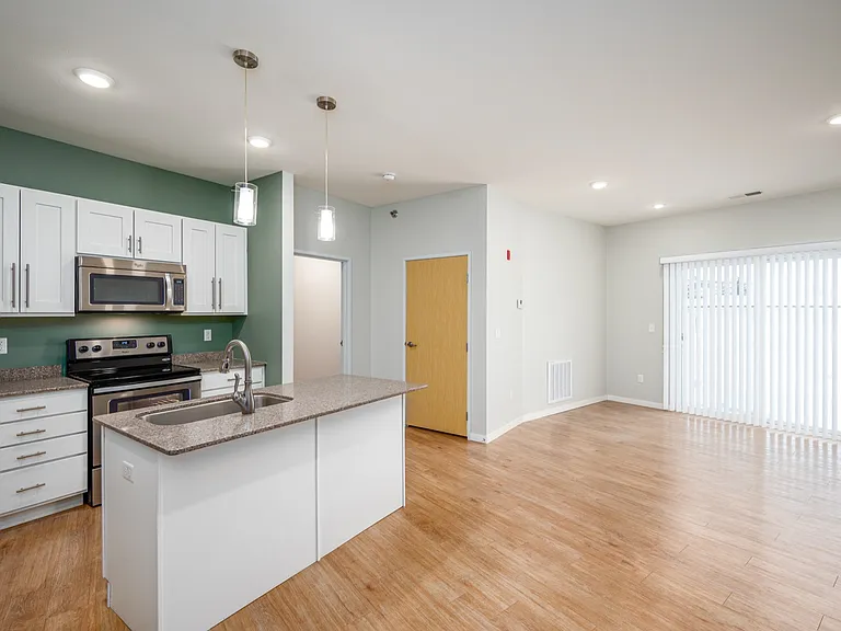 Modern open-plan kitchen and living area featuring sleek white cabinetry, stainless steel appliances, and elegant wood flooring. Modern open-plan kitchen and living area featuring sleek white cabinetry, stainless steel appliances, and elegant wood floorin