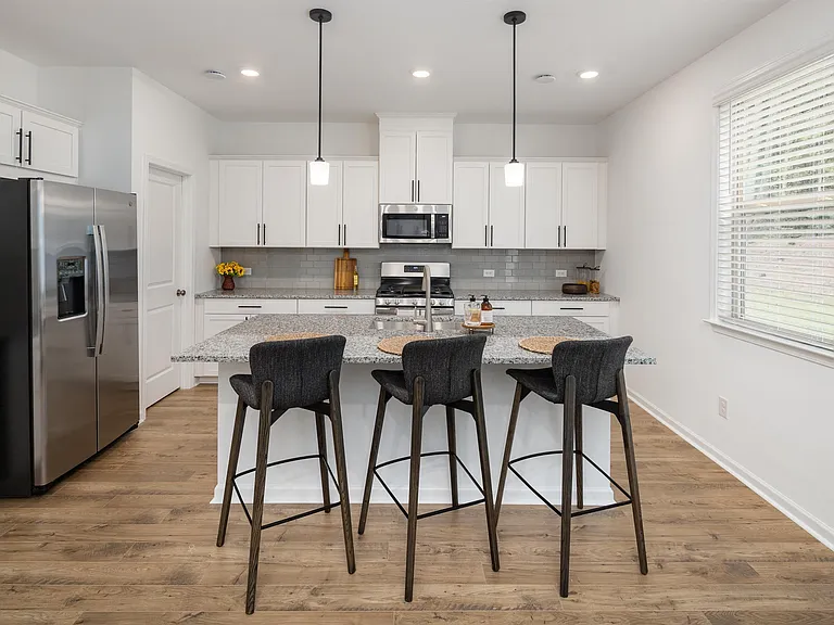 View of the kitchen and entry hallway. Offering bar seating, plenty of cabinet space and granite countertops.
