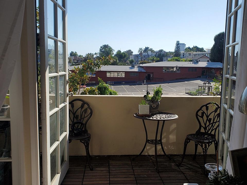 Balcony with French doors, two chairs and small table.