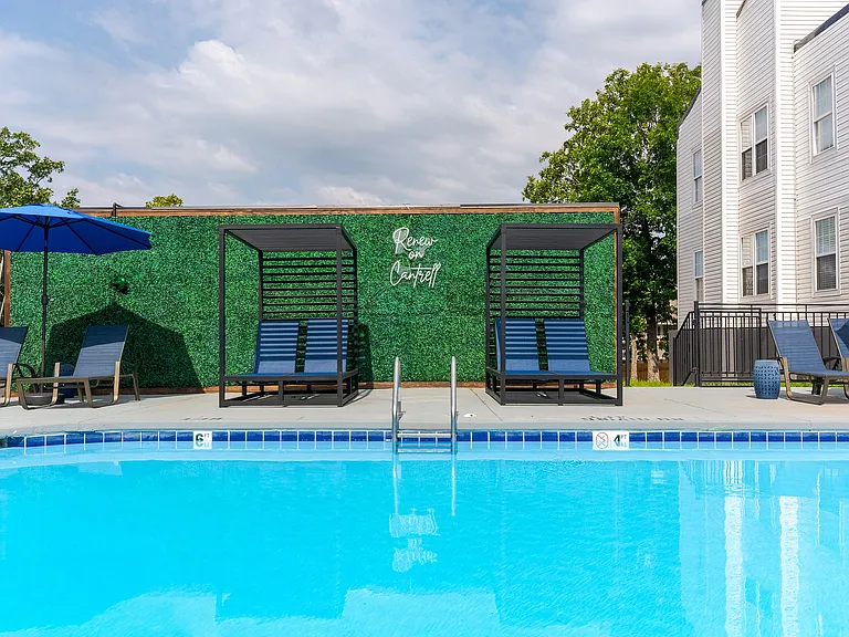 A sparkling swimmin gpool with sundeck and tandem chaise lounge chairs is shown at ReNew on Cantrell.