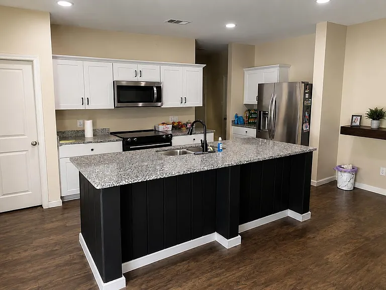 Open kitchen with oversized island, granite-look counters, stainless appliances, and ample cabinet storage.