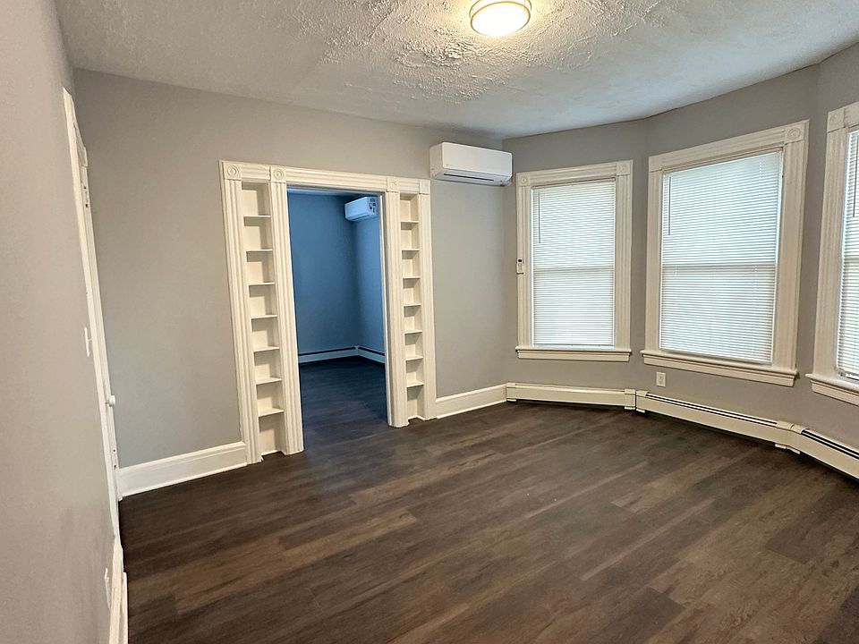 Center room with three windows with blinds, built-in shelves and walk-in closet.