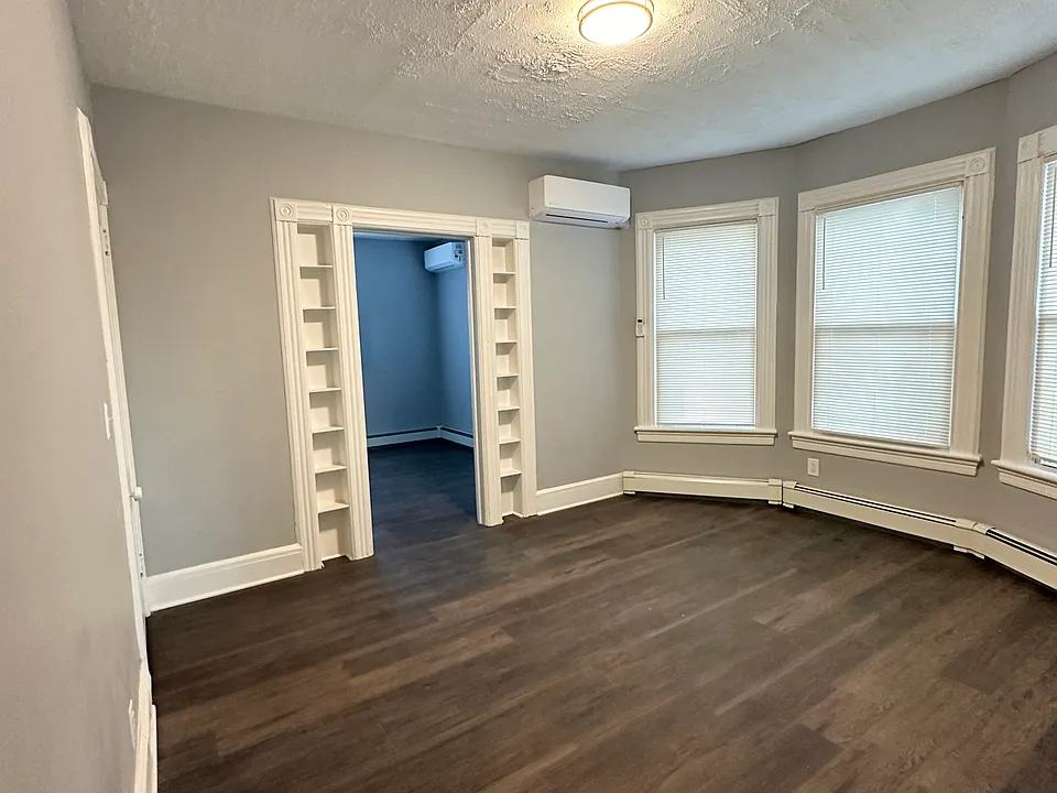 Center room with three windows with blinds, built-in shelves and walk-in closet.