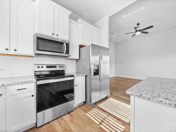 The kitchen has white wood cabinetry.