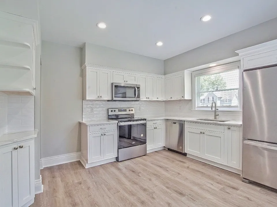 Custom kitchen cabinets with white calacatta quartz countertops and whirlpool stainless steel appliances.