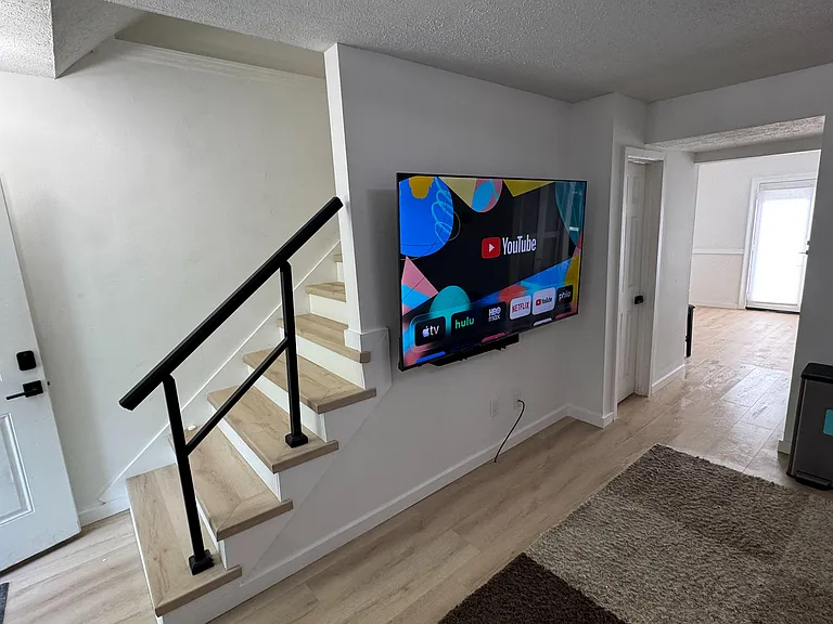Entry hallway with stair access, durable flooring, and a wall-mounted TV, connecting easily to the main living areas.
