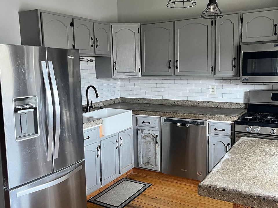 Kitchen with farm sink, concrete counter tops, and stainless steel appliances