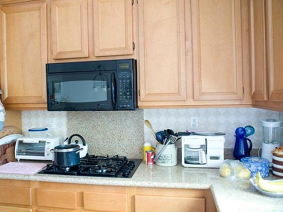 Older photo. Kitchen showing light wood cabinets, light colored faux granite counters and black appliances. Cook top is gas appliance.