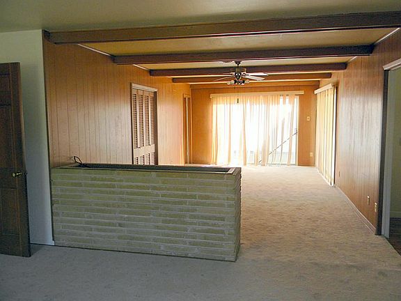 Huge living room with large window panels allowing lots of sunlight and warmth into the room. Clean, neutral carpet throughout and brick half-wall divider separating the living from the dining room.