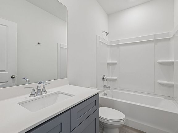 The secondary bathroom features a large vanity and oversized shower tub.