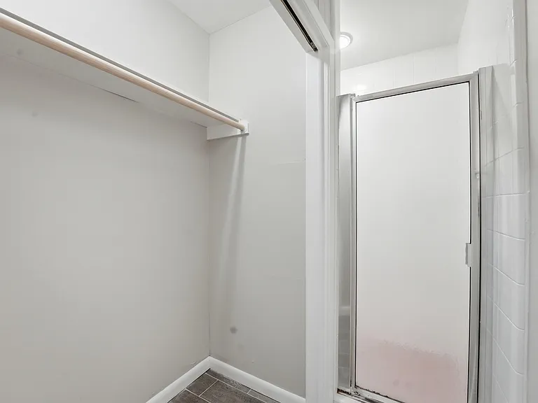 Cedar-lined closet area with hanging rod and shelf storage, finished with tile flooring and access to an adjoining bath.