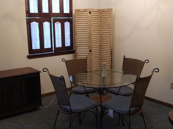 Dining area with custom window treatments, decorative privacy screen, vintage stereo, table and chairs.