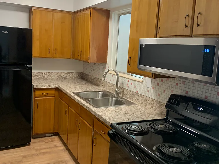 Kitchen has brand new black appliances: refrigerator, microwave, and stove.