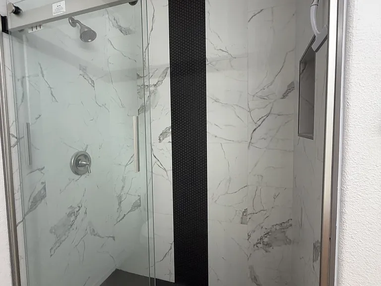 Walk in shower for the primary bedroom with shower glass doors.