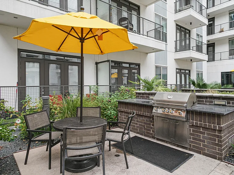 Outdoor grilling area with ample gathering space and shaded areas near the pool